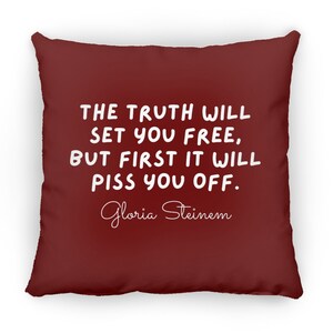 May include: A maroon throw pillow with white text that reads "THE TRUTH WILL SET YOU FREE, BUT FIRST IT WILL PISS YOU OFF." The text is in a handwritten font. Below the text is the name "Gloria Steinem" in a cursive font.