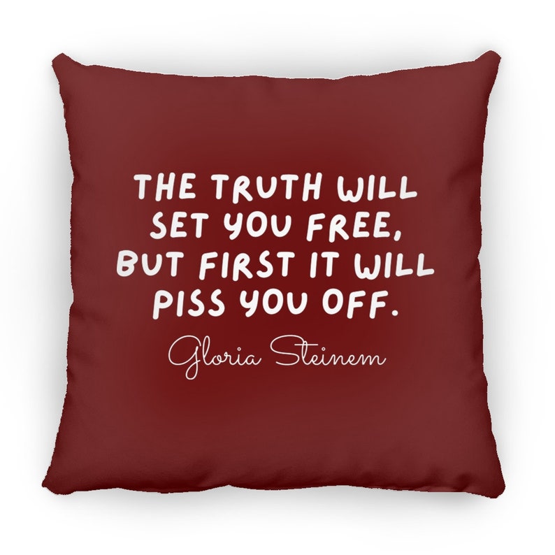 May include: A maroon throw pillow with white text that reads "THE TRUTH WILL SET YOU FREE, BUT FIRST IT WILL PISS YOU OFF." The text is in a handwritten font. Below the text is the name "Gloria Steinem" in a cursive font.