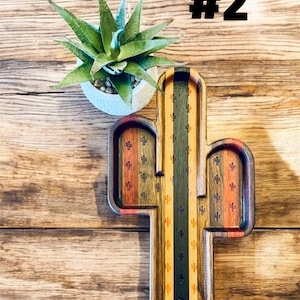 May include: A wooden cactus-shaped tray with a multi-colored design, including green, orange, and brown stripes. The tray has a central section and two side sections. A small potted succulent plant sits nearby. The text "#2" is in the top right corner.