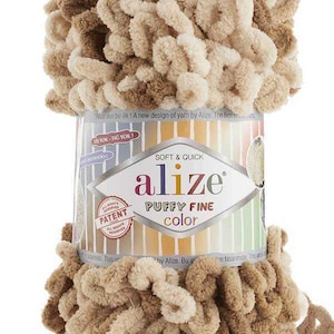 Puede incluir: Un ovillo de hilo esponjoso de color marrón y beige, etiquetado como "alize puffy fine color". El hilo es suave y rápido de trabajar, y es perfecto para crear proyectos acogedores.