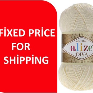 Peut inclure: Une pelote de fil Alize Diva effet soie, de couleur blanc cassé. L'étiquette présente le nom de la marque et les détails du produit. Le texte "FIXED PRICE FOR SHIPPING" est sur fond rouge.