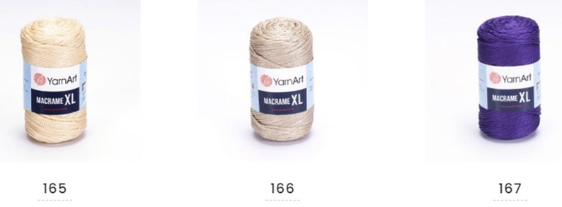 May include: Three spools of yarn in different colors: beige, gold, and purple. Each spool has a label that reads "YarnArt Macrame XL".