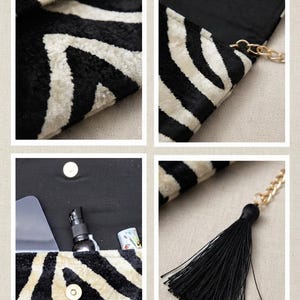 Puede incluir: Un bolso de mano con estampado de rayas de cebra en blanco y negro y acabado texturizado. El bolso incluye un cierre magn&eacute;tico dorado, un forro interior negro y una correa de cadena dorada adornada con una borla de tela negra.