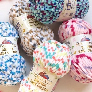 May include: A selection of Himalaya Dolphin Baby Colors yarn balls in various shades. The yarn appears soft and fluffy, with colours such as blue, pink, brown, and mixed hues. Each ball has a label displaying the brand name and product information.