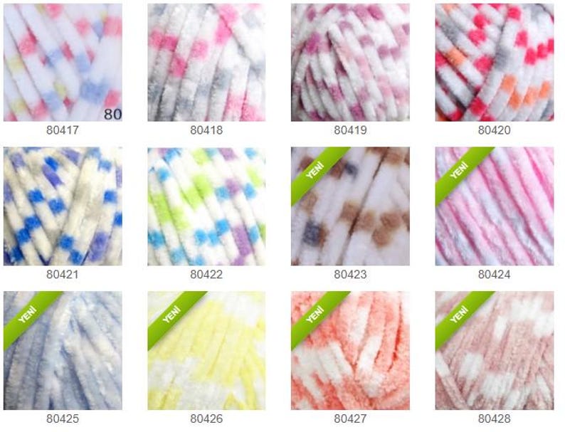 May include: A selection of yarn skeins in various colours and patterns. The yarn has a soft, textured feel, with shades of blue, pink, white, and yellow. Each skein is labelled with a product code. Ideal for knitting and crochet projects.