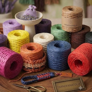Puede incluir: Múltiples bobinas de hilo de rafia de colores en tonos rosa, amarillo, naranja, azul, rojo, verde, morado y beige. Se incluyen una pequeña cesta tejida, un llavero trenzado, unas tijeras de metal y una placa de la marca YARNOFANATOLIA.