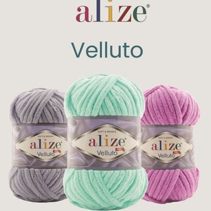 Op de afbeelding: Drie bollen Alize Velluto garen in grijs, mintgroen en roze. Het garen is zacht en helder, met de merknaam en productnaam op de verpakking. Het Alize-logo staat bovenaan.