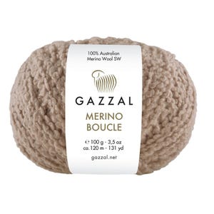 May include: A ball of Gazzal Merino Boucle yarn in a light brown shade. The label states "100% Australian Merino Wool SW." It weighs 100 g and is approximately 120 meters long. The brand name and yarn type are clearly visible.