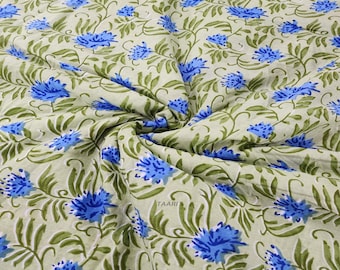 May include: A close-up of a light green fabric with a blue floral print. The fabric is folded and the print is visible on both sides.