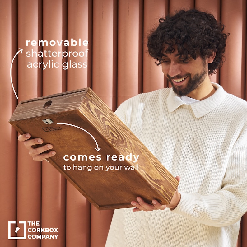 May include: A person holds a wooden frame with a removable shatterproof acrylic glass front. The frame is ready to hang on a wall. The text "comes ready to hang on your wall" is printed on the frame.