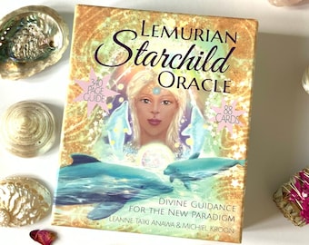May include: A box of Lemurian Starchild Oracle cards with a 340-page guide and 88 cards. The box features a colorful illustration of a young girl with blonde hair and blue eyes surrounded by dolphins. The text on the box reads "Lemurian Starchild Oracle", "Divine Guidance for the New Paradigm", and "Leanne Taiki Anawa & Michiel Kroon".