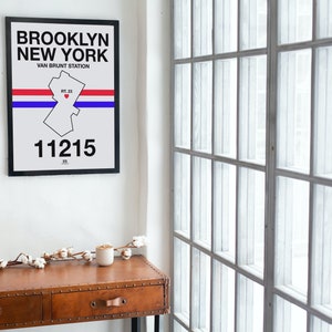 May include: A black framed print with a white background and black text that reads "BROOKLYN NEW YORK VAN BRUNT STATION 11215". The print also features a white outline of the Brooklyn borough with a red heart in the center.
