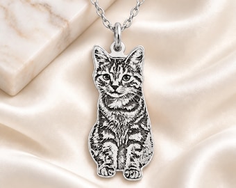 Puede incluir: Un collar con colgante de metal plateado que presenta un retrato grabado y detallado de un gato atigrado. El colgante cuelga de una cadena plateada a juego. El texto PAWS & KNIGHT aparece impreso en la esquina inferior derecha.