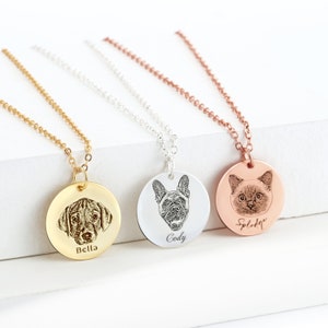 Puede incluir: Tres collares personalizados con retratos de mascotas. Uno dorado con un retrato de perro y el nombre "Bella", uno plateado con un retrato de perro y el nombre "Cody", y uno oro rosa con un retrato de gato y el nombre "Splodge".