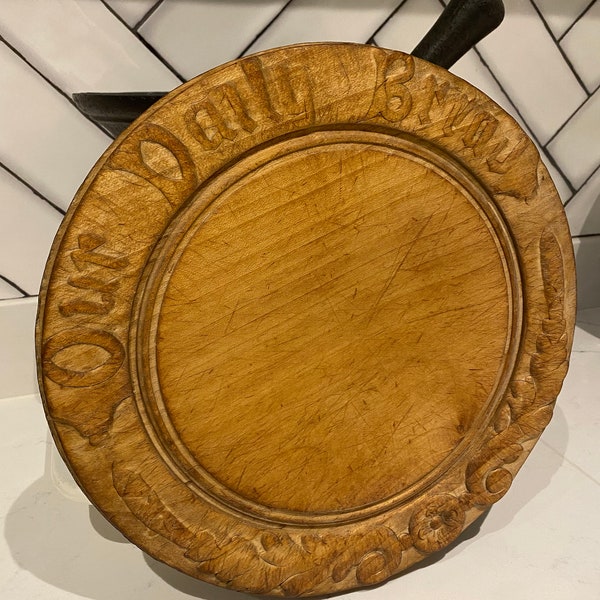Antique bread board with carved “Our daily bread” motto around the border.