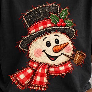 Könnte beinhalten: Ein schwarzes T-Shirt mit einer Grafik eines lächelnden Schneemanns, der einen schwarzen Zylinder mit rot-weiß kariertem Band, einen passenden rot-weiß karierten Schal, eine Karottennase, eine braune Pfeife und grüne Stechpalmenblätter trägt.