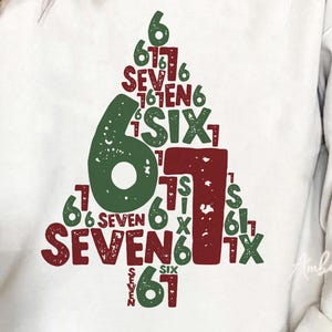 May include: Cream-colored sweatshirt with a Christmas tree design made of the number 6 and the word "SIX" in green and the number 1 and the word "SEVEN" in burgundy. The text "61" is also present in green.
