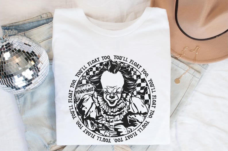 May include: White t-shirt with a black and white graphic of Pennywise the clown from the movie "IT". The graphic features the text "You'll float too" repeated around the edge of the circle.