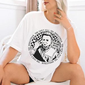 May include: White t-shirt with a black and white graphic of Michael Myers from the Halloween franchise. The graphic is a circle with the text "THE BOOGEYMAN. YOU CAN'T KILL THE BOOGEYMAN. YOU CAN'T KILL THE BOOGEYMAN." around the outside.