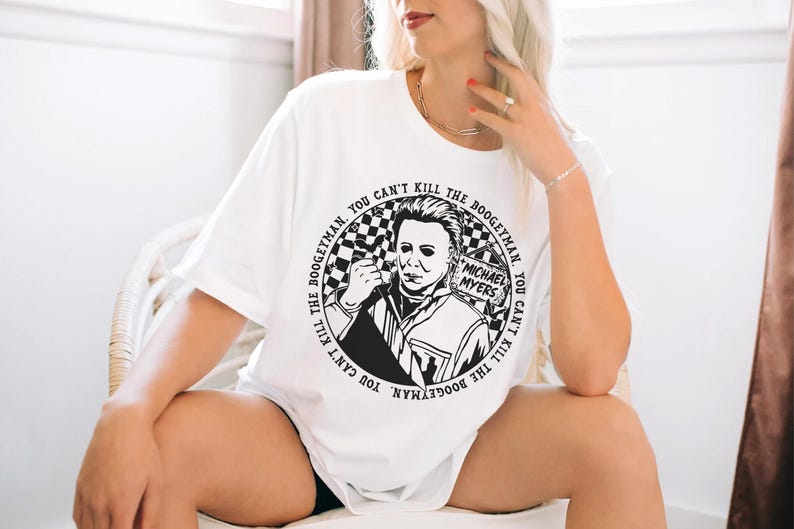May include: White t-shirt with a black and white graphic of Michael Myers from the Halloween franchise. The graphic is a circle with the text "THE BOOGEYMAN. YOU CAN'T KILL THE BOOGEYMAN. YOU CAN'T KILL THE BOOGEYMAN." around the outside.