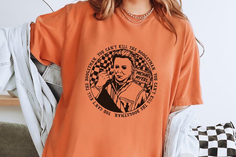 May include: Orange t-shirt with a black and white graphic of Michael Myers from the Halloween franchise. The graphic features the text "You can't kill the boogeyman. You can't kill the boogeyman."