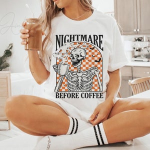 May include: White t-shirt with a graphic of a skeleton holding a coffee cup and the text "Nightmare Before Coffee".