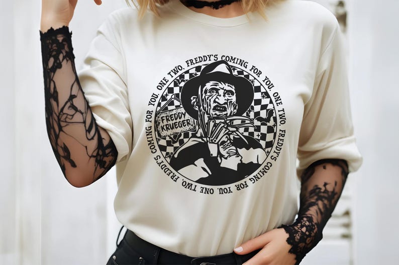 May include: White long-sleeve shirt with a black and white graphic print of Freddy Krueger from the movie A Nightmare on Elm Street. The graphic features the text "Freddy's Coming for You. One Two, Freddy's Coming for You. One Two, Freddy's Coming for You."