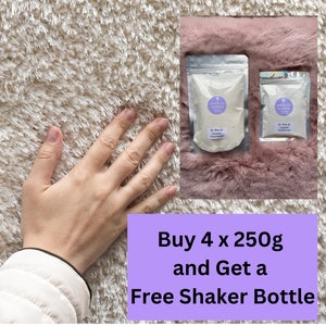 Op de afbeelding: Twee doorzichtige zakjes tapijtreiniger met de tekst "ANGELIC SCENTS" en een paars logo. De zakjes liggen op een roze, pluizig oppervlak. De tekst "Buy 4 x 250g and Get a Free Shaker Bottle" staat op een paarse achtergrond.