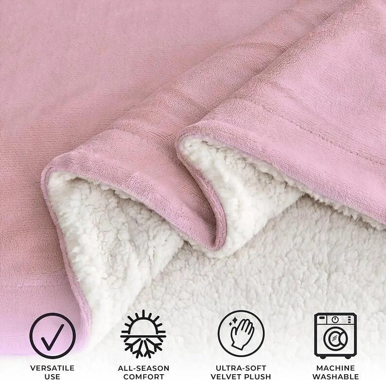 May include: A pink blanket with a soft, plush exterior and a white, fluffy interior. The blanket is folded to show the contrasting textures. The image includes icons indicating versatile use, all-season comfort, ultra-soft velvet plush, and machine washable.