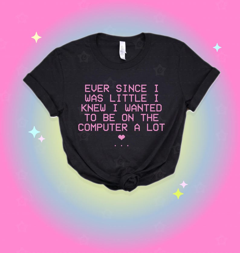 May include: A black short-sleeved t-shirt featuring the pink pixelated text: EVER SINCE I WAS LITTLE I KNEW I WANTED TO BE ON THE COMPUTER A LOT, followed by a small pink heart and three dots. The shirt has a crew neckline and a standard fit.