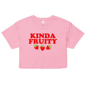 May include: Pink cropped t-shirt with the text "Kinda Fruity" in red letters and three red strawberries with green leaves.