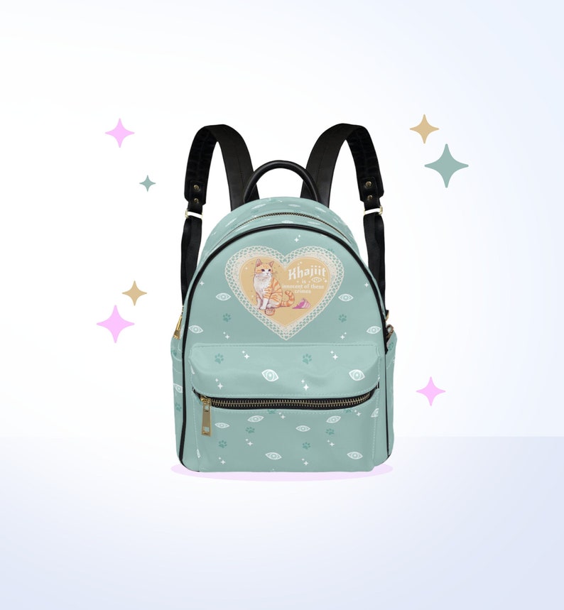 May include: A light blue backpack with a black zipper and straps. The backpack has a pattern of eyes and paw prints. The front of the backpack features a heart-shaped design with a cat inside and the text "Khajiit,  The Way of the  Cat".