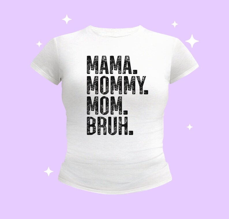 May include: A white short-sleeved t-shirt featuring black distressed-style text centered on the chest that reads MAMA. MOMMY. MOM. BRUH. The garment has a crew neckline and a fitted silhouette, presented against a light purple background with white stars.