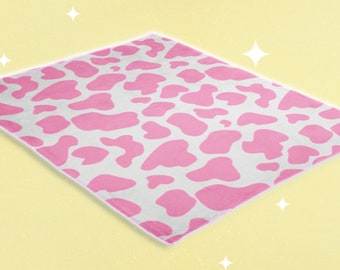Può includere: Una coperta in pile rosa e bianca con stampa a mucca. La coperta è morbida e soffice ed è perfetta per coccolarsi sul divano.