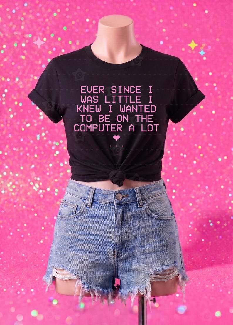 May include: A black short-sleeved t-shirt with a knotted hem featuring the pink text "EVER SINCE I WAS LITTLE I KNEW I WANTED TO BE ON THE COMPUTER A LOT" and a small pink heart, paired with light blue distressed denim shorts with a frayed hem.