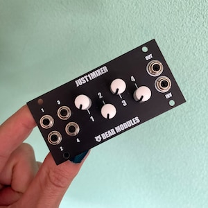 Puede incluir: Un módulo de mezclador de audio negro con el texto "JUST1MIXER" y "BEAR MODULES" impreso en él. El módulo tiene cuatro perillas con perillas blancas y cuatro conectores de 1/4 de pulgada.