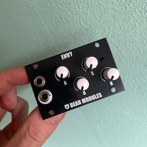 Könnte beinhalten: Ein schwarzes elektronisches Musikmodul mit weißen Knöpfen, die mit "A", "D", "S" und "R" beschriftet sind. Das Modul ist mit "Envy" und "Bear Modules" beschriftet.