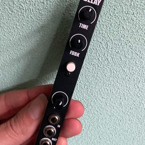 May include: Black metal effects pedal with knobs labelled "Time" and "Fdbk" and jacks labelled "In", "Wet", and "Mix". The pedal has the word "DELAY" printed on it.