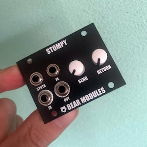 Puede incluir: Módulo de efectos StompY negro con botones blancos etiquetados como "Send", "Return" y "FX". El módulo tiene cuatro conectores de 1/4 de pulgada etiquetados como "Synth", "FX", "Out" y "FX". El módulo está etiquetado como "BEAR MODULES".