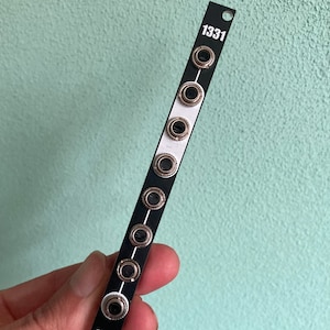 May include: A black electronic module with the number "1331" printed on it. The module has eight silver jacks on the front.