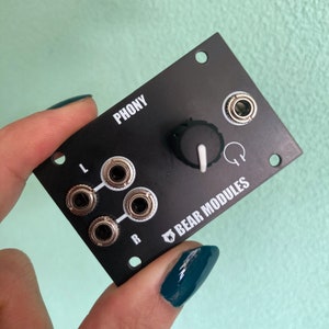 Puede incluir: Módulo de audio negro 'Phony' con una perilla y tres conectores de 6,35 mm etiquetados como 'L' y 'R'. El módulo está etiquetado como 'Bear Modules'.