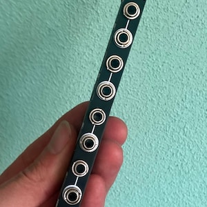 Puede incluir: Gráfico en blanco y negro de la cabeza de un oso en un módulo negro con el texto "PLUS MINUS" y ocho conectores plateados.