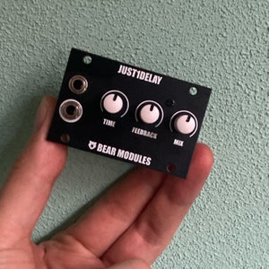Op de afbeelding: Zwarte Just1Delay audio-effectmodule met drie knoppen met de labels "Time", "Feedback" en "Mix". De module is gemaakt door Bear Modules.