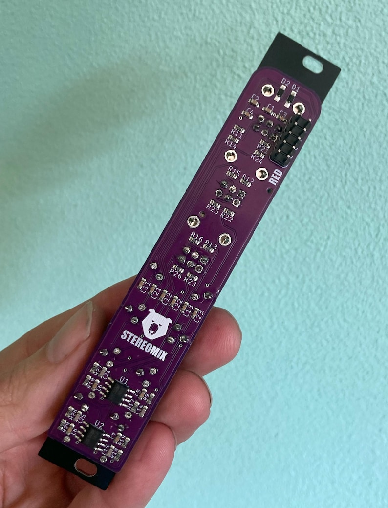 May include: A purple circuit board with the text "STEREOMIX" and a bear logo. The board has several components, including resistors, capacitors, and integrated circuits. The board is labeled with the text "RED" and "O2 01".