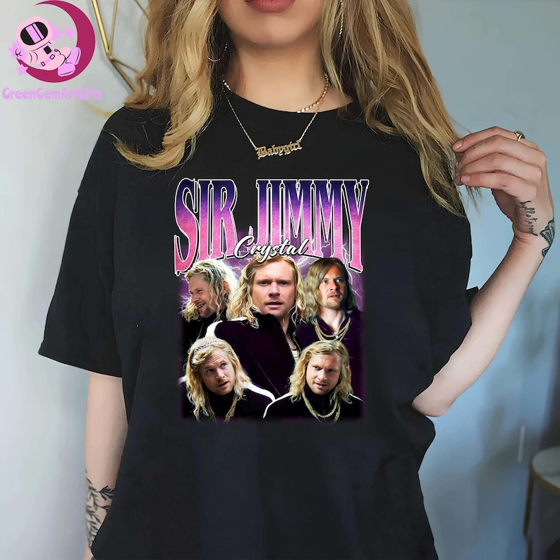 May include: Black t-shirt featuring a graphic of Sir Jimmy Crystal with a retro design. The design includes the text "SIR JIMMY Crystal" in a purple and pink font, along with multiple images of the character.