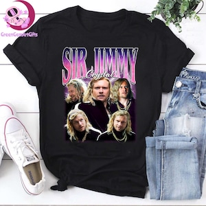May include: Black t-shirt featuring a graphic of a man with long blonde hair, with the text "SIR JIMMY Crystal" in a retro font. The design includes multiple images of the man. The shirt is paired with blue jeans and white sneakers.