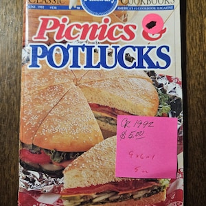 May include: A vintage Pillsbury Cookbooks magazine cover featuring a large sandwich and the title "Picnics & Potlucks." The cover includes text such as "Make It Easy On Yourself!" and "Giant Picnic Sandwich." A pink sticky note is attached.