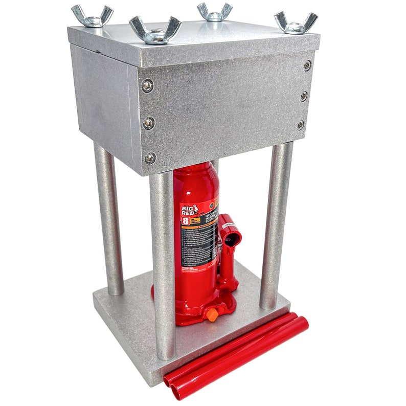 May include: A silver metal hydraulic press with a red hydraulic jack. The press has a square base and a square top with four wing nuts. The jack is labeled "Big Red 6 Ton".