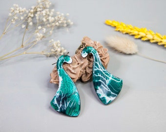 May include: A pair of green and white abstract swirl earrings. The earrings are made of metal and have a unique, organic shape.