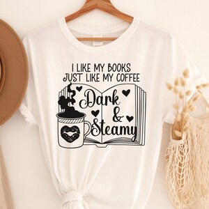 May include: White t-shirt with black text that reads "I like my books just like my coffee Dark & Steamy" with a graphic of a coffee cup and a book.